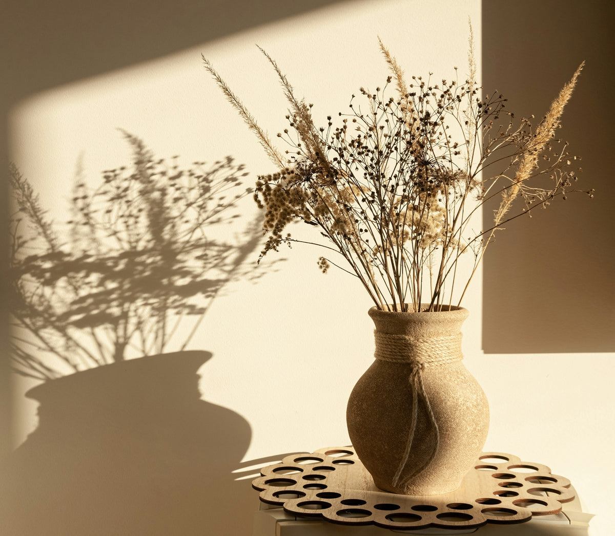 A ceramic vase with dried branches in afternoon light