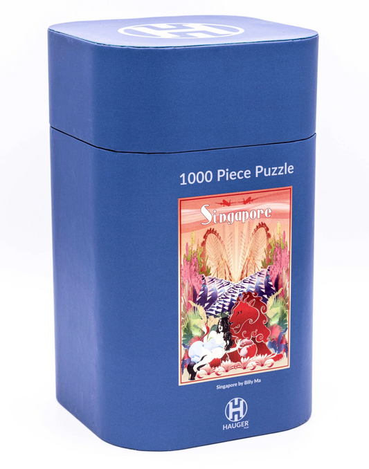 A blue cylindrical puzzle box for a 1000-piece Singapore-themed puzzle, featuring a colorful illustration of a red elephant and tropical scenery on the front, with the HAUKEG brand logo at the bottom.